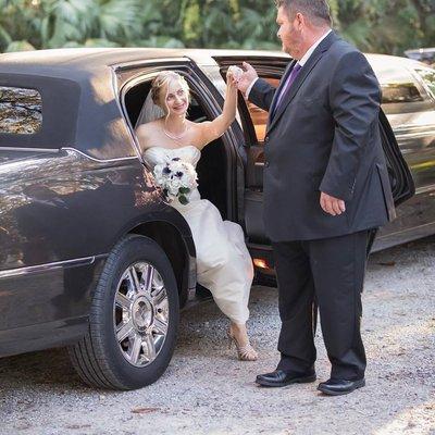 Father of the Bride helps his daughter as she steps out of the limousine