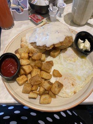 Cowboy breakfast eggs over medium, chicken fried steak, biscuit and potatoes