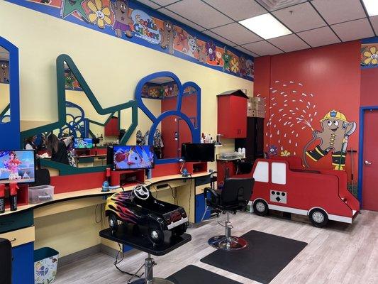 Cute little seats shaped as cars  and little televisions for kids to watch a tv show while they get their haircut ‍