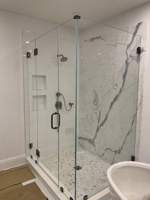 A great combination of a  grey and white marble tile on main floor ,porcelain shower wall framed in Carrara