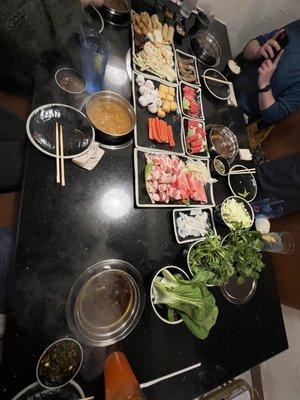 Individual pots with assorted veggies, meats, and seafood