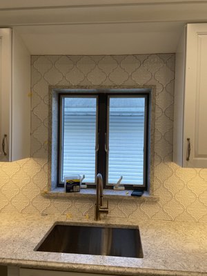 Beautiful crafted window framed in tile with a sill made with the quartz from the counters