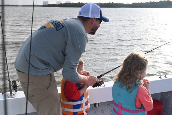 Dad helping son fish in the morning on the water at Marco island