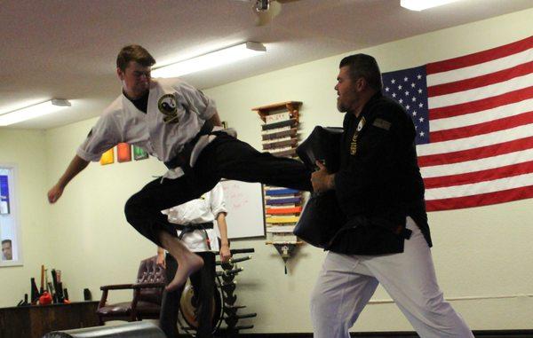 Instructors demonstrating flying kicks to students