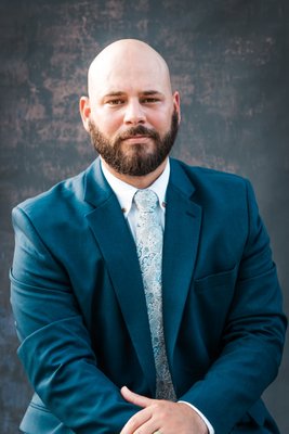 Professional headshot of gentleman in blue suit pictured waist up.