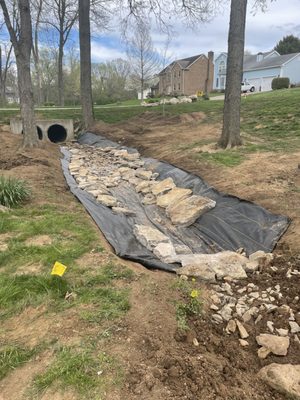 They widened the creek, added a layer of landscaping fabric to keep the dirt from eroding during heavy rain, and finished by adding stone.