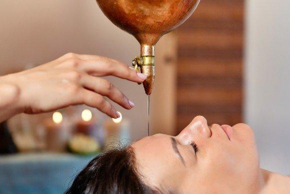 Model demonstrating the Shirodhara oil pouring gently on the forehead