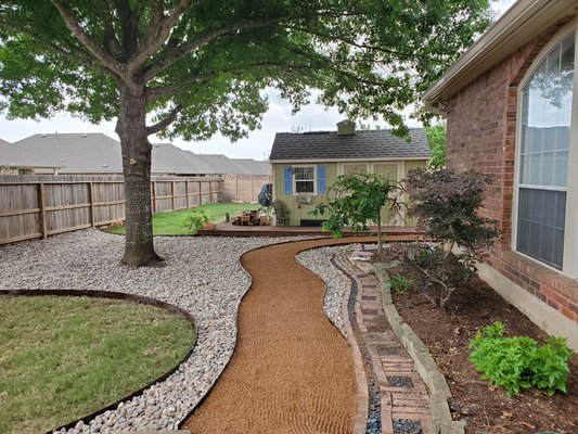 A new decomposed granite path and river rock take place of dead grass and muddy walkway!