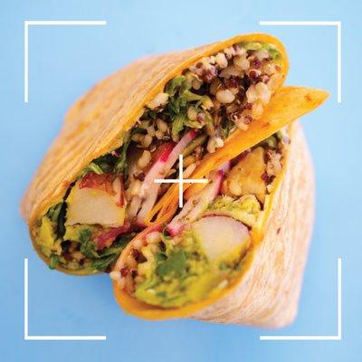 Vitality Wrap with greens, grains, roasted potato, radish, vegan garlic aioli, avocado, hummus on a tomator basil tortilla.