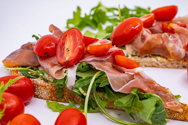 organic fresh local farm to table prosciutto toast on sourdough with cherry tomatoes and arugula