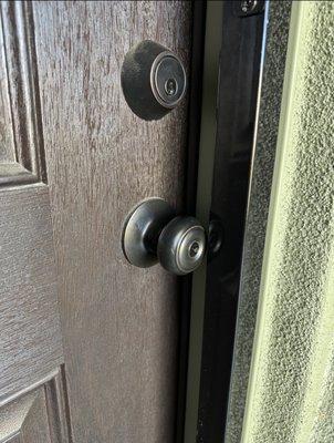 The door knob is touching the wrought iron frame because they installed it on the door jamb