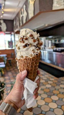 Single scoop of butter pecan frozen custard with homemade waffle cone