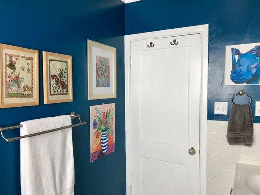 Bold blue paint and personal art make this one boring bathroom interesting.