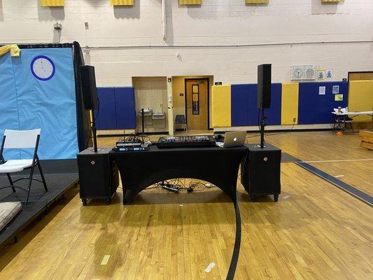 All black DJ equipment setup in a school gymnasium