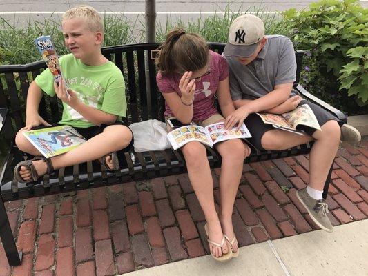 Kids enjoying their new comics on bench in front of the comic shop