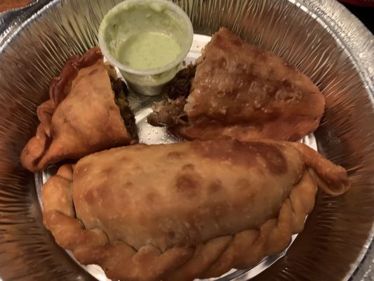 Beef Empanada ( cut in half) with cilantro sauce. The other is a Dulce de Leche empanada. Both were awesome.