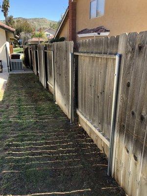 A repair on broken wood post. Steel brace holds up existing fence.