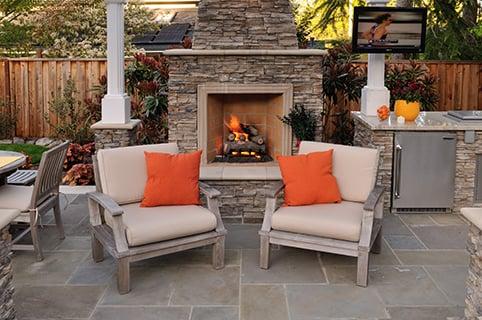 Outdoor fireplace, ashlar pattern bluestone slate paving under custom pergola structure and complete outdoor kitchen