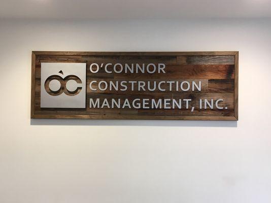 2' x 6' Reclaimed wood sign with laser cut acrylic letters with a surface painted metallic finish installed behind reception counter on wall