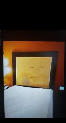 The headboard in Room 208 on the bed nearest the door. Covering was  torn off with foam exposed  covered in filth and something orange.