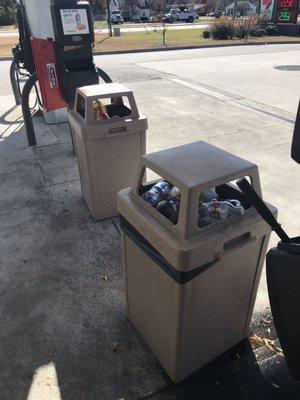 Trash cans over flowing outside, trash in parking lot.