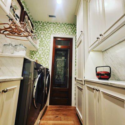 Custom Laundry room. Marble, wallpaper, walnut pocket door, wide white oak flooring.