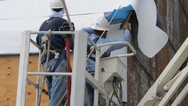 workers using man lift on roof repairs,