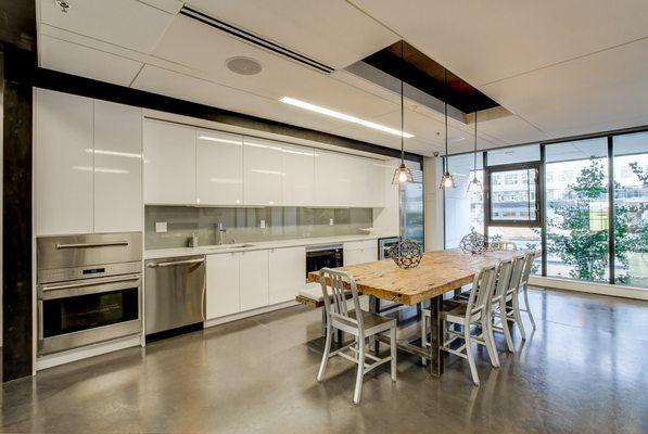 Club room with floor to ceiling windows, a full kitchen and concrete flooring.