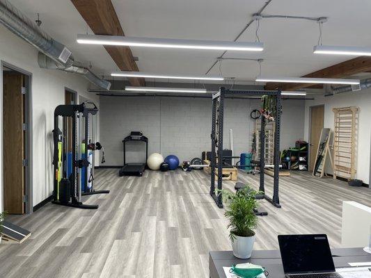 Spacious gym that includes equipment for pilates, unweighted treadmill, BFR, squat rack, and functional trainer.