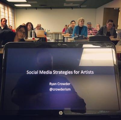 Delivering a workshop to a full room of attentive artists.