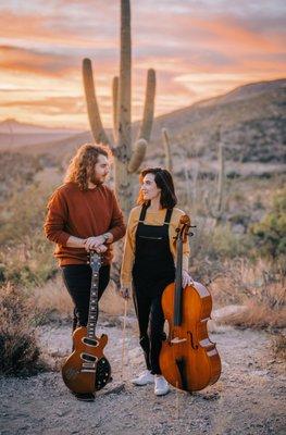 Oliver and Wednesday stand in the desert with their instruments, excited to begin teaching in their new studio!