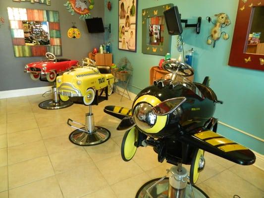 Cute children's styling chairs for haircuts.  Each station is fully equipped with a television for entertainment.