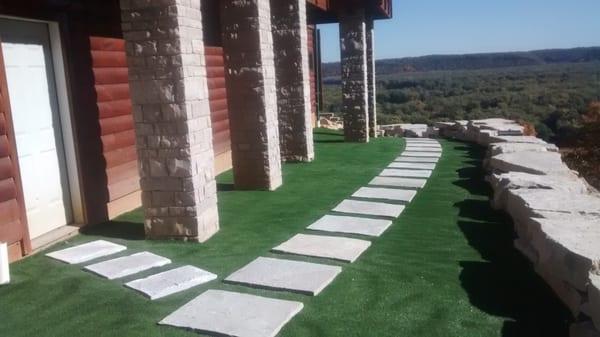 Split face stone columns, artificial grass, natural stepping stones, outcropping seating wall