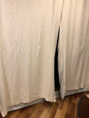 Poorly cleaned linen drapes that cleaner shrunk, note pulling on sides and liner hanging several inches below the drapes.