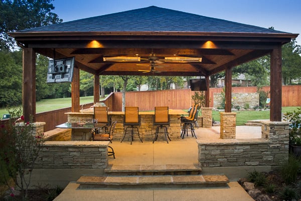 Incredible wrap-around granite countertop and outdoor kitchen protected by a pavilion by Red Valley Landscape & Construction.