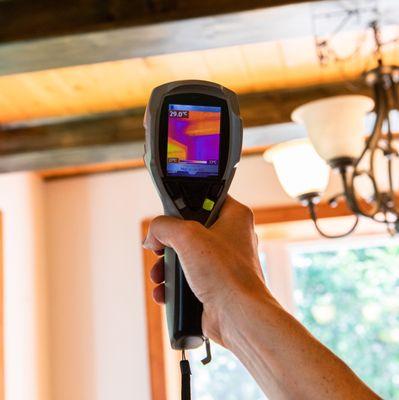 Indoor damp & air quality (IAQ) testing. A handheld IR thermovision camera is seen closeup, checking the insulation levels inside a domestic