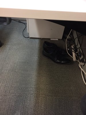 Shoes left right under a desk where customers seats to get service.