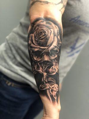 Black and gray skull and rose done on the outer forearm.