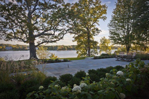 Crafting serene lakefront beauty: Our lush patio oasis surrounded by vibrant greenery offers a perfect retreat for natural relaxation.