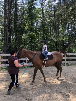 Casey leading the horse and explaining proper technique to the young rider.