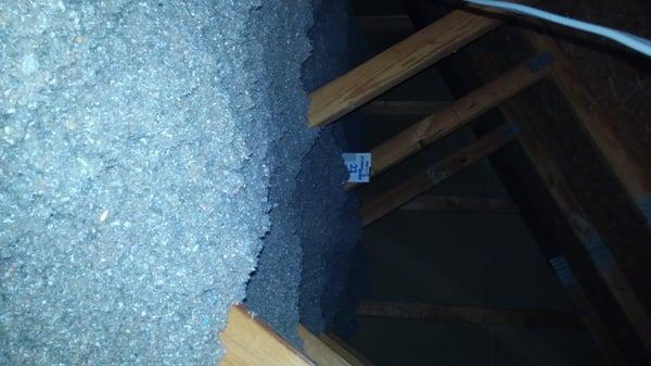 R value ruler in an attic with blown cellulose.