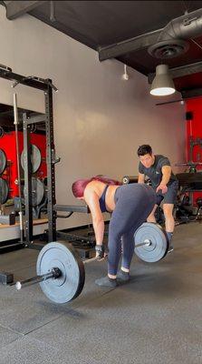 Coach Yong teaching client a Romanian deadlift.