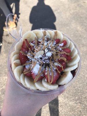 Açaí bowl with fruit, almonds, coconut, peanut butter drizzle.