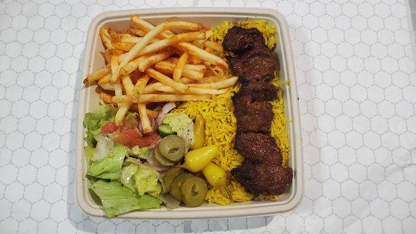 Beef steak kabob plate with rice, salad and fries.