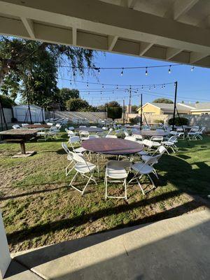 string lights with poles, 66" round table with white folding chairs