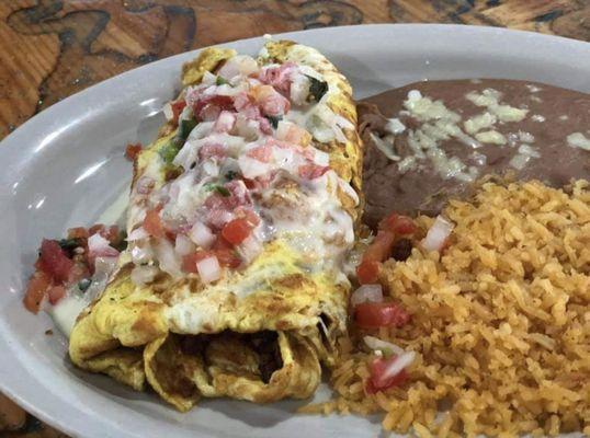 Mexican Omelette. Topped with cheese dip and pico de gallo also served with rice and beans.