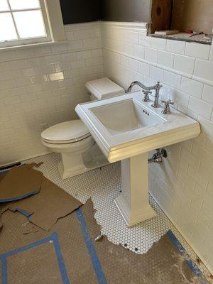 A pedestal sink install with new faucet as well as a new toilet.