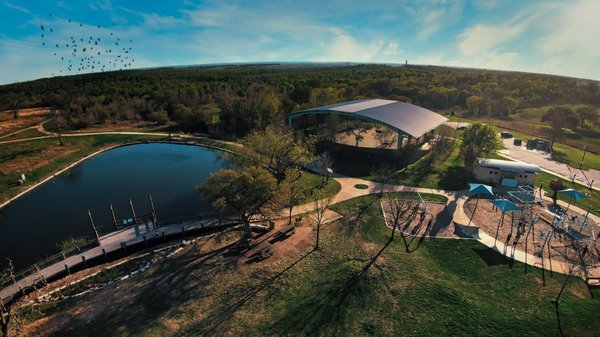 Southwest view of a water feature in the park, including one of two large pavilions available for rent and a playground.