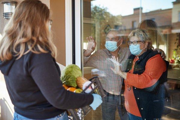 Granddaughter delivers groceries to grandparents.