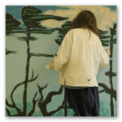 G. Burnett at work on her mural of "Musical Trees"